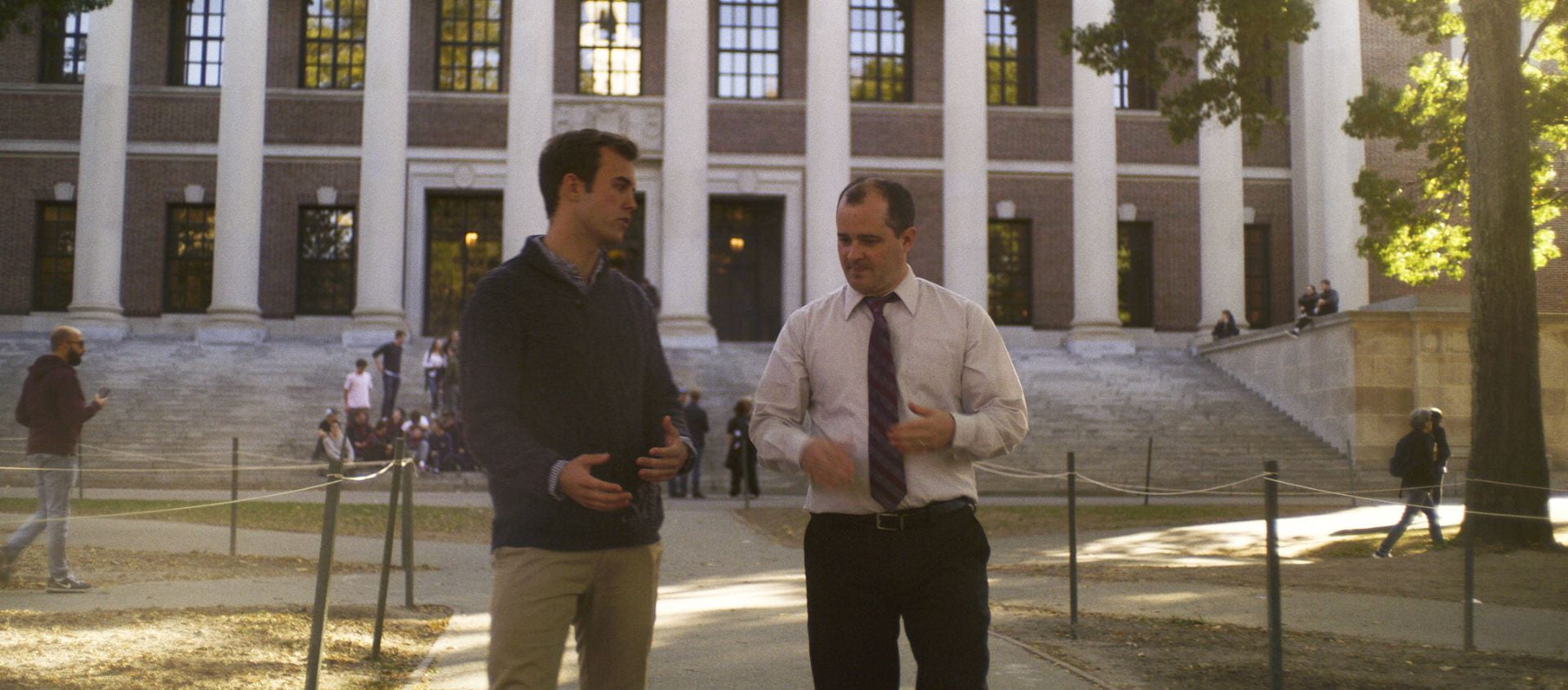 Professor Dustin Tingley and student talking and walking in Harvard yard