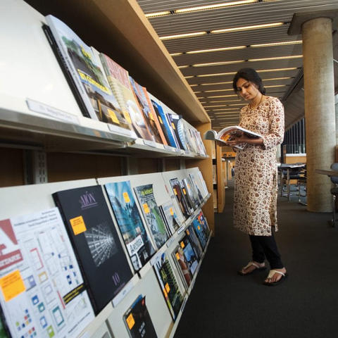 student looking at books in Loeb library